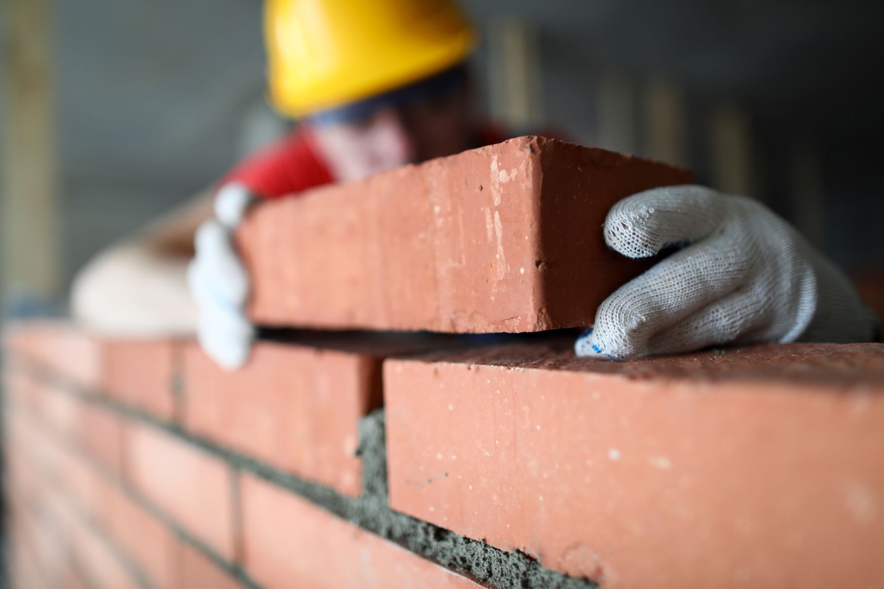 close-up-professional-construction-worker-laying-bricks-industrial-site-builder-protective-uniform-man-building-wall-with-blocks-renovation-concept.jpg